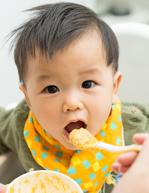 Asian baby being spoon-fed